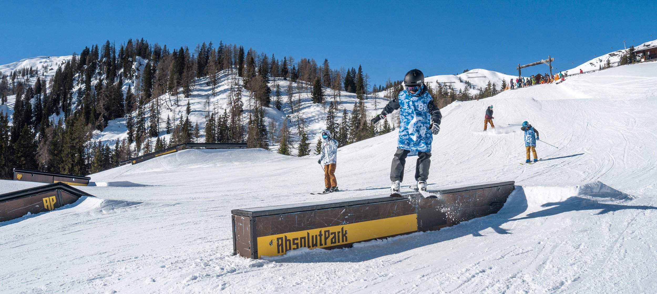 Freeskier zeigt Trick auf einem Rail im Absolut Park. 